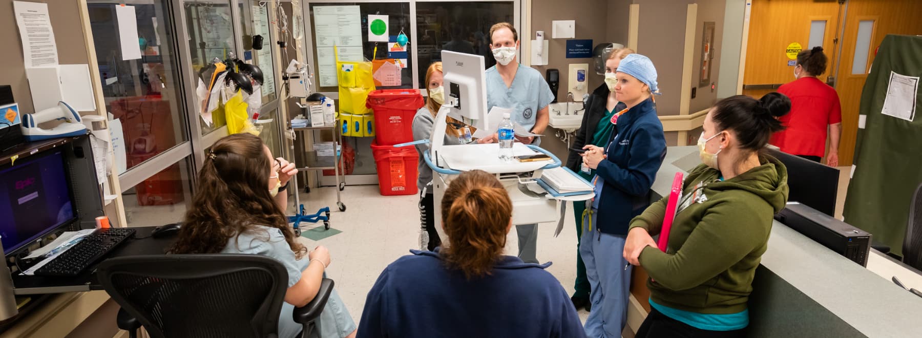 A group of physicians having a discussion on the floor of a hospital unit.